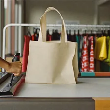Siebdruck: Rakel wird über den Siebdruckrahmen auf eine Stofftasche gezogen