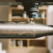 Lasergravur: Laserkopf graviert eine eingespannte Edelstahlflasche