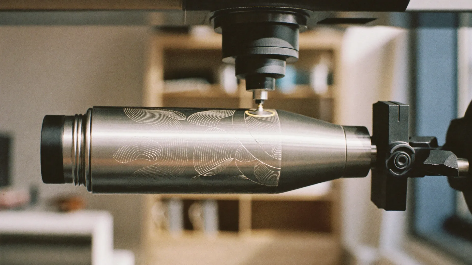 Lasergravur: Laserkopf graviert eine eingespannte Edelstahlflasche